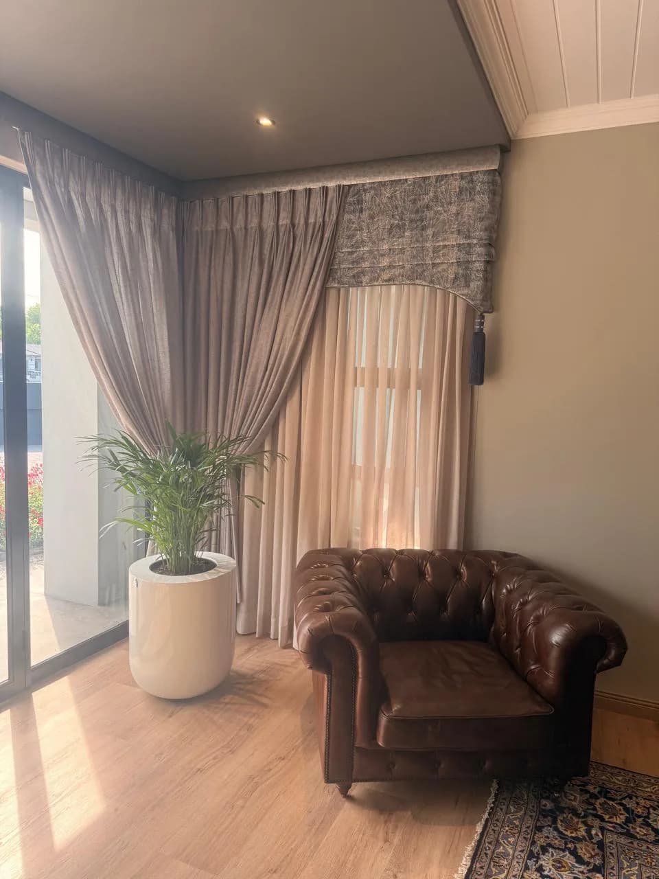Bloem Project Funeral Parlour reception corner with layered sheer curtains, a shaped pelmet, tassel trim and leather armchair