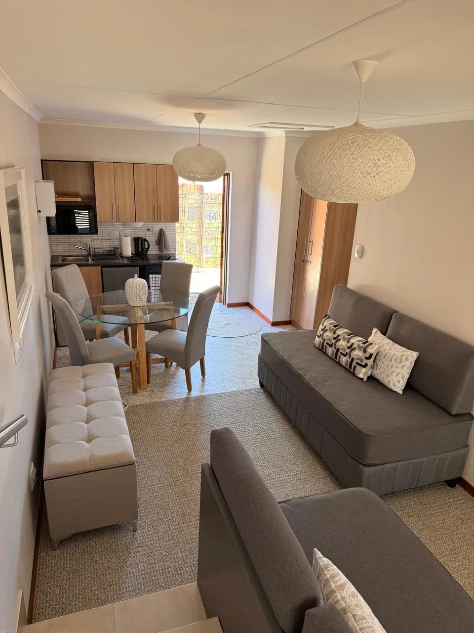 Bloemfontein living and dining room with upholstered seating, ottomans, cushions and pendant lighting