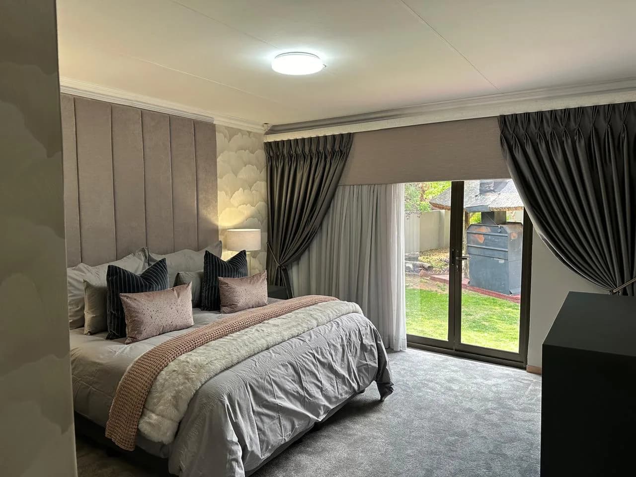 Bloemfontein bedroom with an upholstered headboard, layered bedding, curtains and bedside lighting