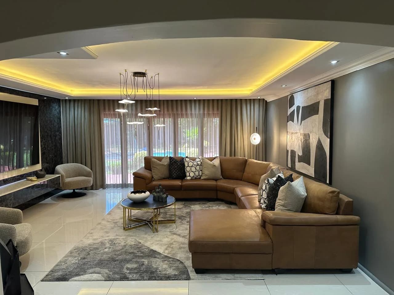 Bloemfontein living room with a leather sectional, rugs, media unit, curtains and warm LED lighting