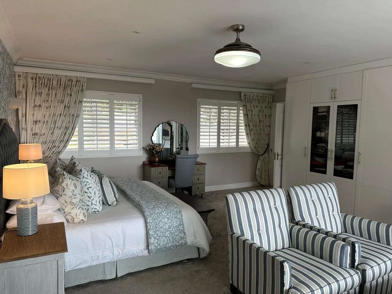Durban bedroom interior with patterned curtains, upholstered chairs and fitted storage