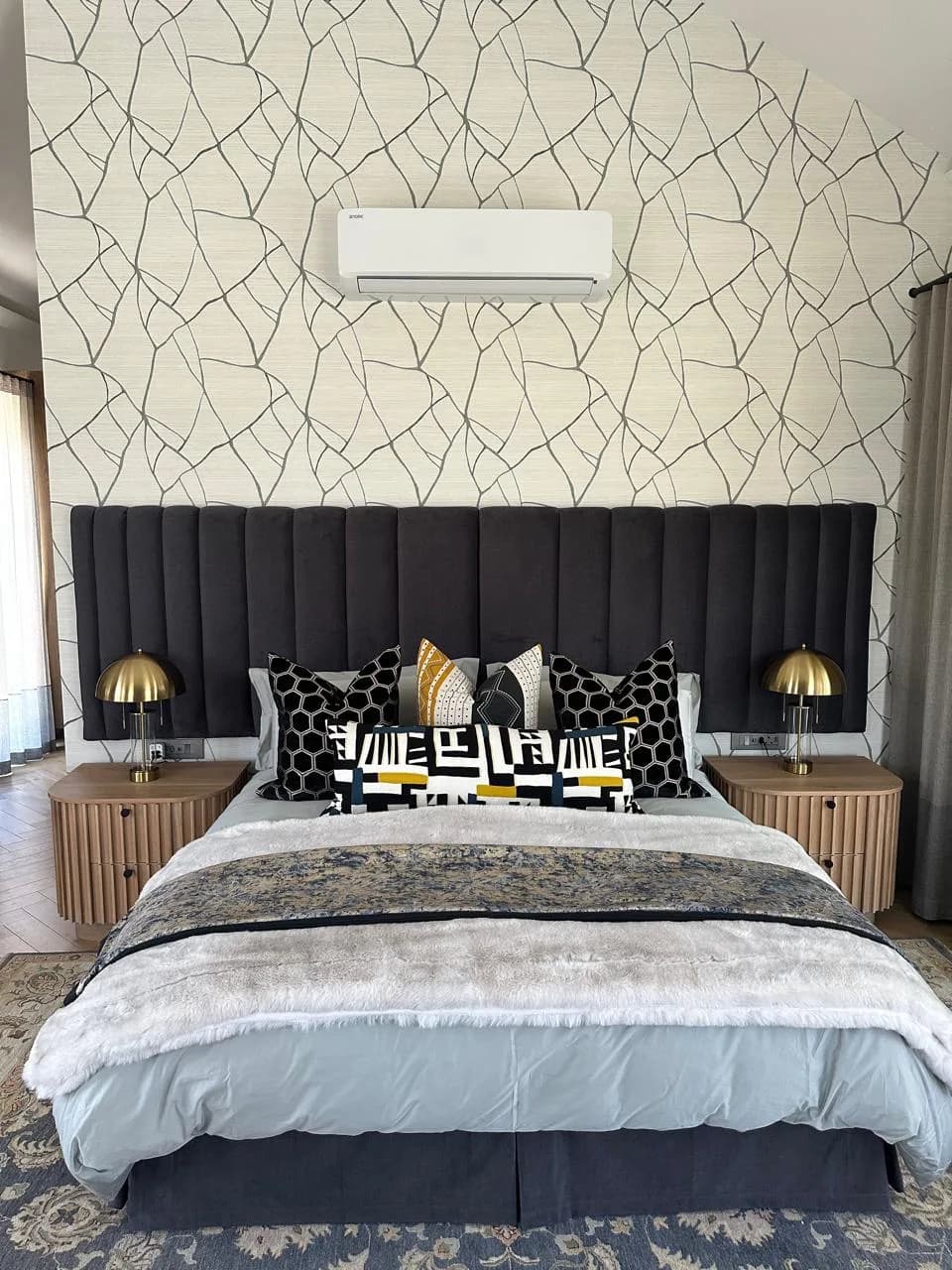 Paarl bedroom with patterned wallpaper, an upholstered headboard, layered bedding and bedside lamps
