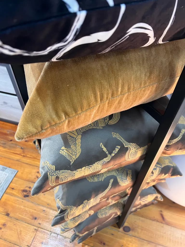 Stacked patterned cushions displayed on a showroom rack.