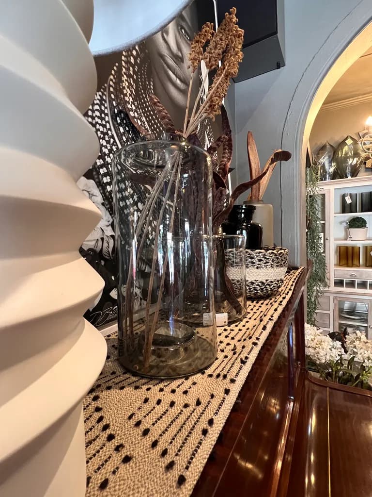 Decorative glass vases, dried stems and patterned runner in the showroom.