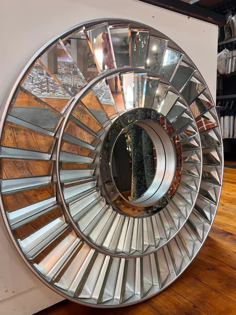 Large circular mirror displayed on wooden showroom flooring.