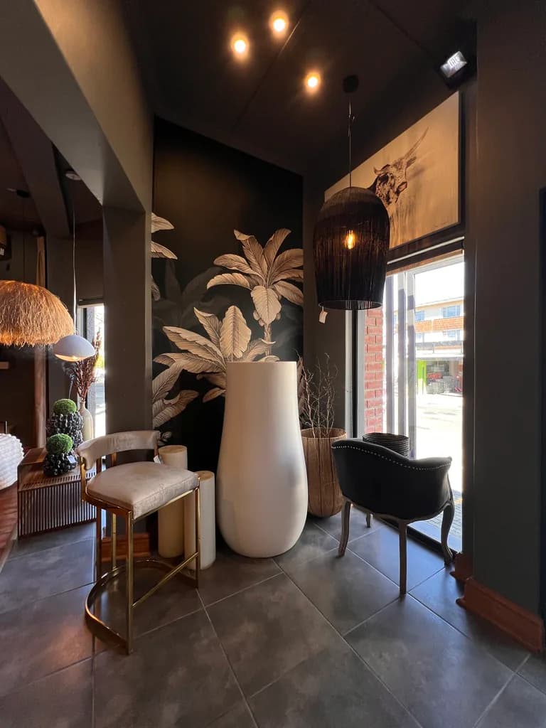 Showroom vignette with wallpaper, chairs, lighting and decorative vases.