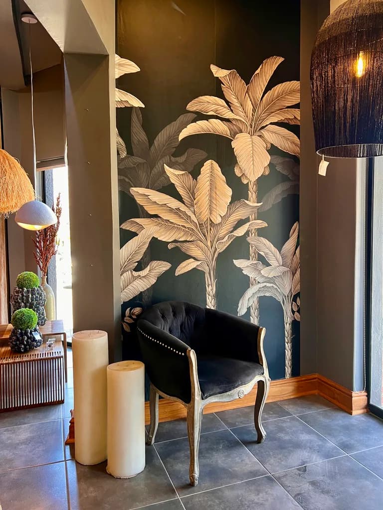 Showroom corner with botanical wallpaper, chair, candles and lighting.
