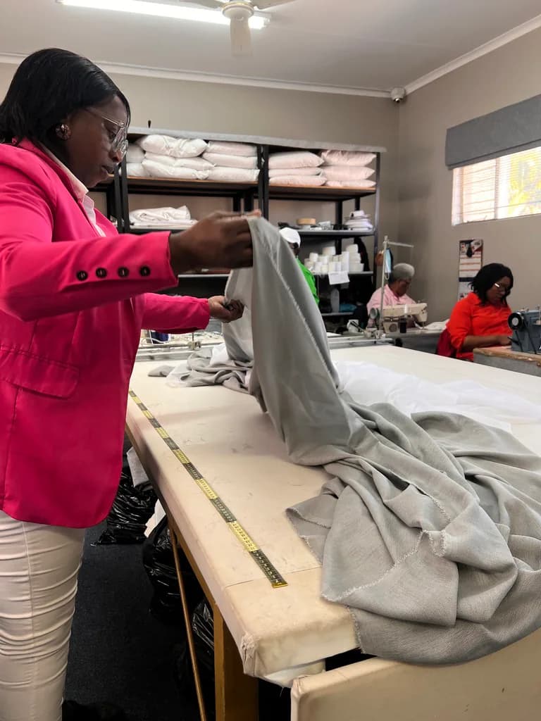 Workshop team member checking finished curtain fabric on a long table.