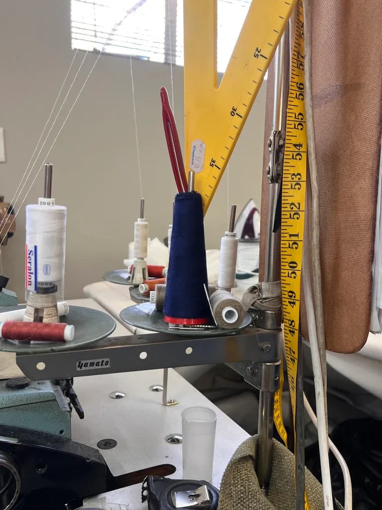 Workshop sewing machine with thread cones and measuring tape.