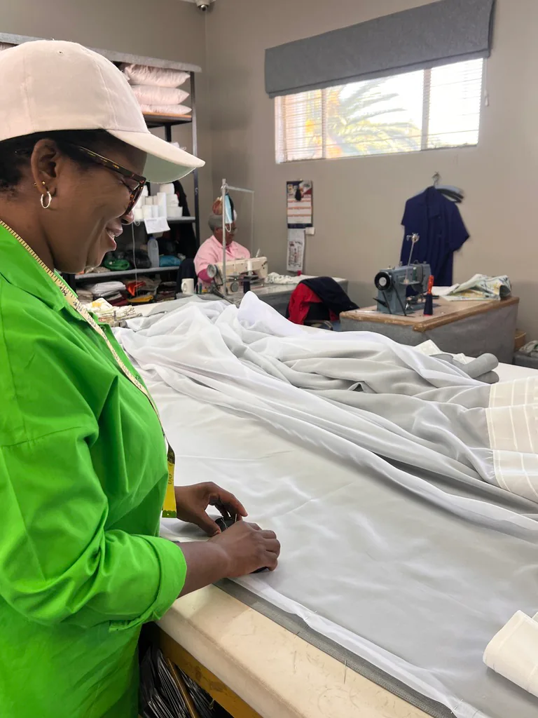 Workshop team member preparing light fabric on a cutting table.