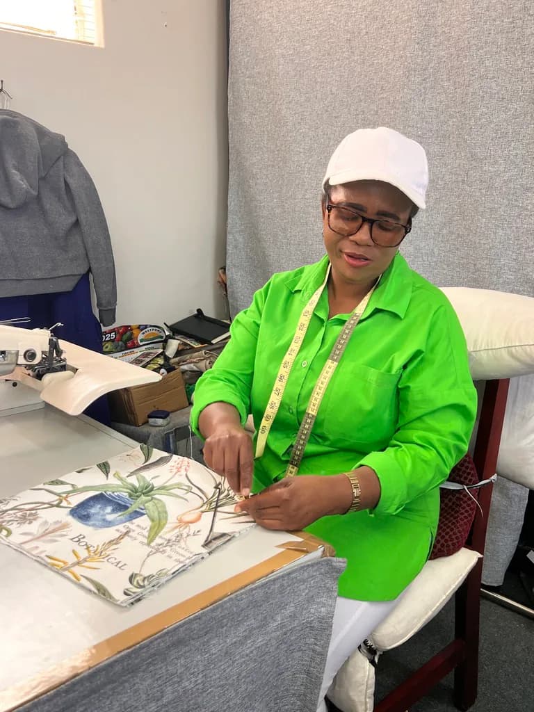 A workshop team member finishing patterned fabric details by hand.